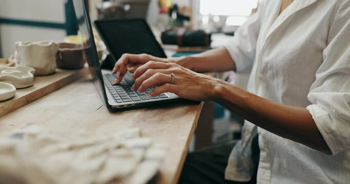 Woman, hands and typing with laptop for online order, communication or inventory at ceramic store. Closeup, female person or artisan writing with computer for art, craft or pottery at clay workshop