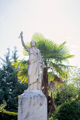 Classical statue with a bird perched on its raised hand outdoors