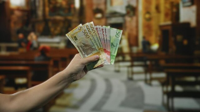 Man holding norwegian krone banknotes inside a church, illustrating the diverse uses of currency within religious indoor settings.