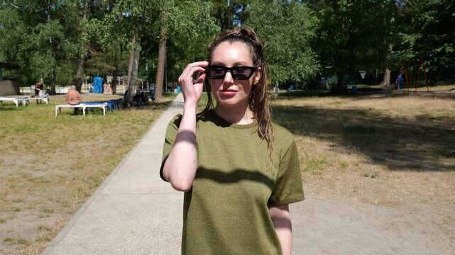 Portrait young woman in green t-shirt in sunglasses walking. Sporty woman. slow motion portrait