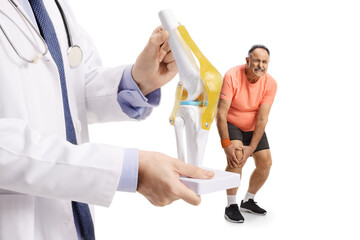 Doctor holding a knee bone model and mature man with leg pain standing behind