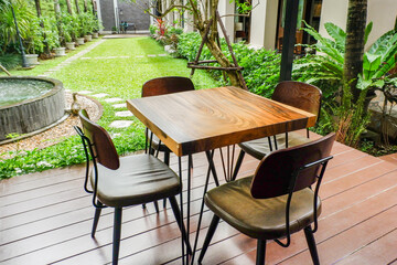 Wooden table and chair set in garden on a sunny day,outdoor seating for restaurant or cafe,Neat paved patio with sitting area and small garden in forest..