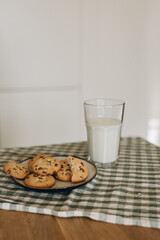a cozy, inviting scene with a plate of freshly baked cookies and a glass of milk placed beside it