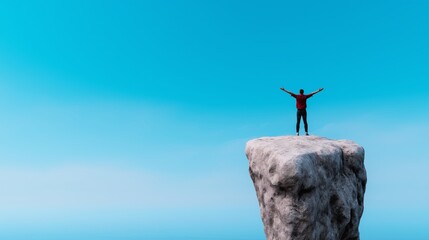 Person standing triumphantly at the cliff's edge with arms raised against a clear blue sky