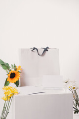 Bag with gift card and a sunflower with different flowers on a white background.