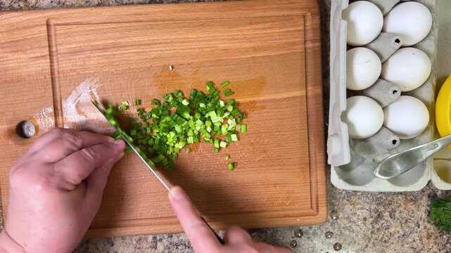cutting green onions with a knife on a wooden