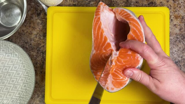 cutting salmon fish with a knife for further