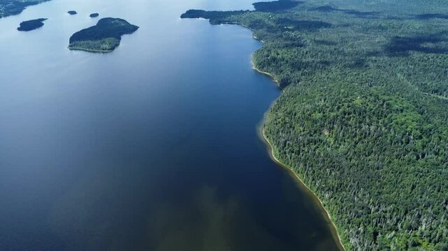 Panoramic aerial view of an immense freshwater lake dotted with green islands up to a sandy point creating a sandy beach. Lac Matapedia, Quebec, Canada.