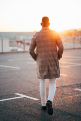 Businessman walking away at sunset in parking lot