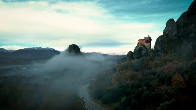 Meteora is a rock formation with a complex of Orthodox monasteries perched on its peaks. Foggy early morning. Greece.