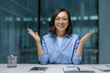 Webcam view, joyful Asian woman looking into the camera, smiling contentedly talking to colleagues...