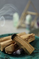 Smoldering palo santo stick and gemstone on table, closeup