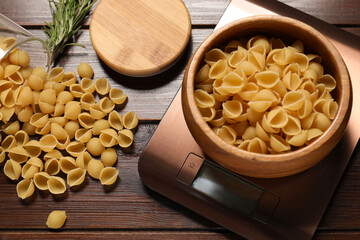 Electronic kitchen scale and products on wooden table, closeup