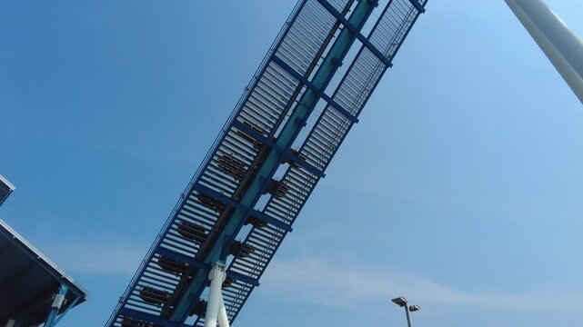 People Enjoying a Thrilling Ride on a Rollercoaster Against a Blue Sky