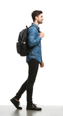 Fototapeta premium A confident young male commuter walks with a backpack, wearing casual attire, captured from the side, isolated on a clean white background for a modern feel, isolate white background