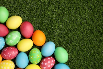 Beautiful decorated Easter eggs on green grass, flat lay. Space for text