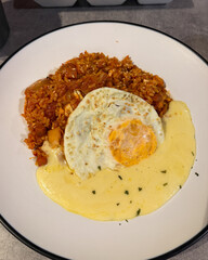 A plate of kimchi fried rice with egg and cheese.