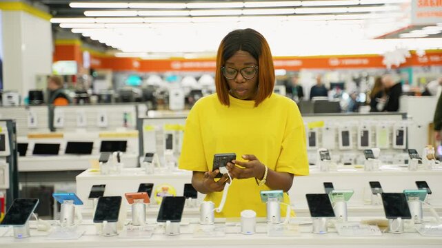 African American woman choosing a smartphone in tech store
