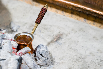 Natural ground coffee is brewed in copper turk on coals according to Turkish tradition, close-up, copy space