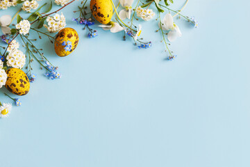 Easter flat lay. Stylish easter eggs and spring flowers on blue background, space for text. Easter...