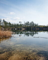Quarry lake with rocky banks on a sunny day. Reflection of trees and sky in water of flooded granite open-pit quarry. © andrbk