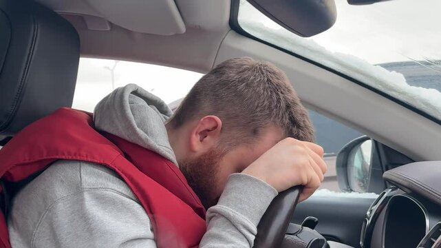 Young tired exhauster man is sleeping in the car