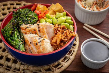 
Ceramic pot with Poke made from gyoza rice, green soy, chicken, broccoli, sweet potato, on a straw mat