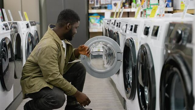 Man examining a washing machine in an appliance store