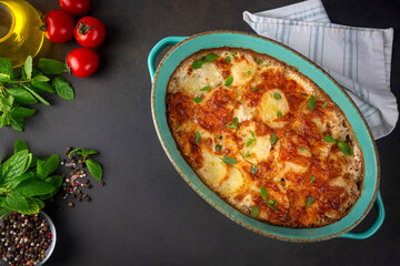 Potato gratin - graten (baked potatoes with cream and cheese) with rosemary and forks (Turkish name; Kremali patates)