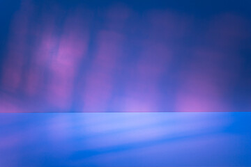  Empty table on smooth blue wall background. Composition with abstract pink light reflections and blue shadows. Mock up for winter presentation, branding products, cosmetics and food.