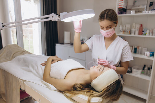 Cosmetologist performing a filler injection treatment on a client's forehead for skin rejuvenation and wrinkle reduction