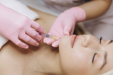 Cosmetic professional injecting dermal filler into patient's chin, enhancing facial contours and youthful appearance