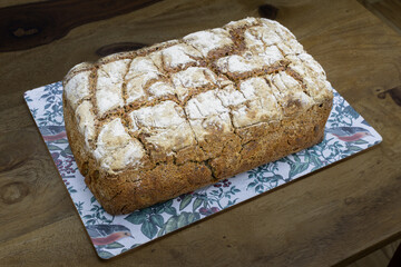 A loaf of homemade sourdough rye bread sits on a wooden table