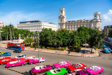 A row of vibrant classic convertible cars is parked near the Museum of the Revolution in Havana,...