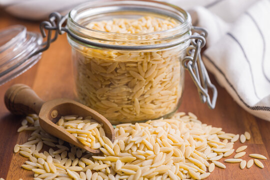 Orzo, kritharaki, risoni pasta. Uncooked dry pasta on wooden table.