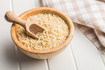 Orzo, kritharaki, risoni pasta. Uncooked dry pasta in bowl on white table.