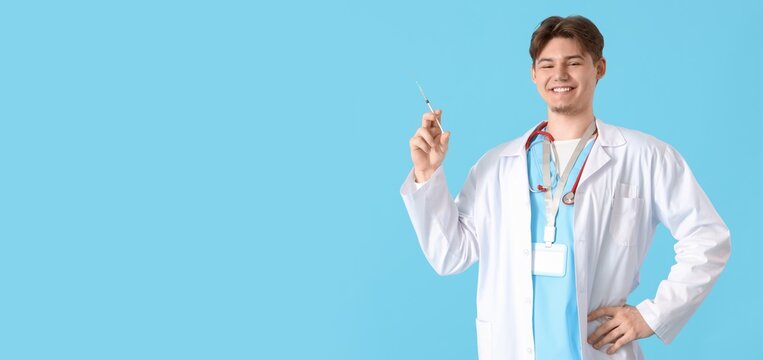 Male doctor holding syringe on light blue background with space for text. Vaccination concept