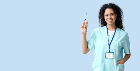 African-American nurse holding syringe on light blue background with space for text