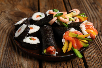 Plate with tasty sushi cones and rolls on wooden background