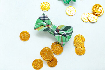 Bow tie and golden coins on light background. St. Patrick's Day celebration