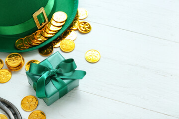 Leprechaun hat with gift and golden coins on white wooden background. St. Patrick's Day celebration