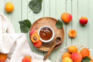 Bowl with sweet apricot jam on green wooden background