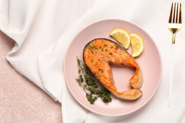 Plate of tasty salmon steak with lemon on beige background