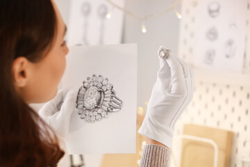 Female jewelry designer working with sketch of stylish ring at workplace