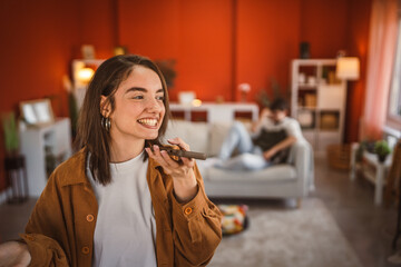 young beautiful woman record voice mail on mobile phone at home