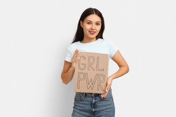 Young woman with sign GRL PWR on white background. Feminism concept