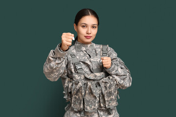 Young female soldier in fight stance on green background. Feminism concept