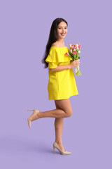 Happy young Asian woman with bouquet of beautiful tulips on purple background. International Women's Day
