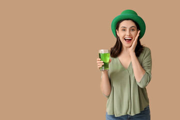 Happy young woman in leprechaun hat with glass of beer on brown background. St. Patrick's Day...
