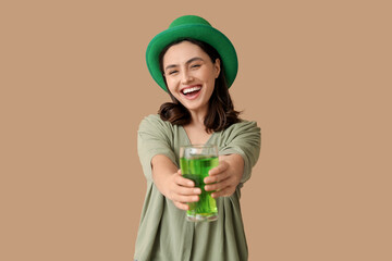Happy young woman in leprechaun hat with glass of beer on brown background. St. Patrick's Day...